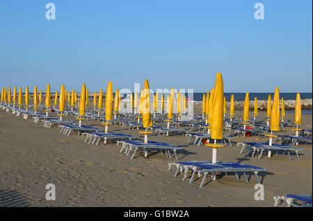 Fermé jaune parasols sur la plage avec chaises longues et transats Banque D'Images