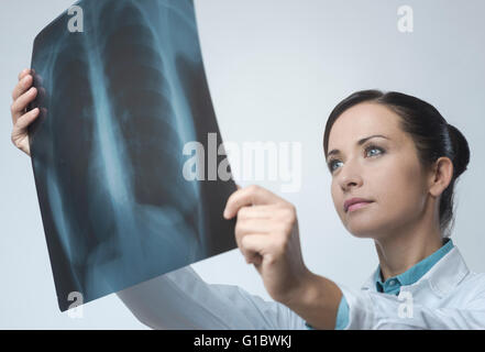 Confident female doctor examining précisément une cage thoracique x-ray. Banque D'Images