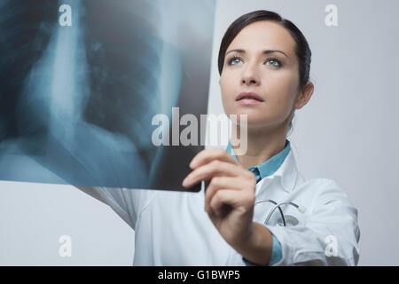 Confident female doctor examining précisément une cage thoracique x-ray. Banque D'Images