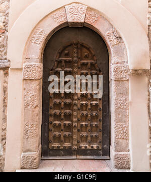 Entrée voûtée d'un palais médiéval avec porte en bois sculpté. Banque D'Images