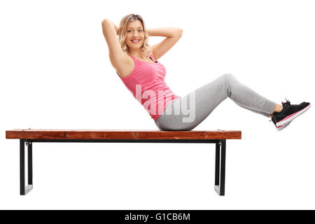 Faire de l'athlète féminine abdominal crunches sur un banc et regardant la caméra isolé sur fond blanc Banque D'Images