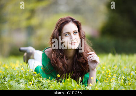 Happy smiling teenage girl lying on the Green grass Banque D'Images