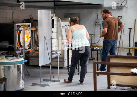 Les travailleurs de soufflage de verre en verre à un chauffage en usine, Devon, UK Banque D'Images