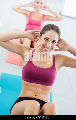 Jeune fille sportive au gymnase faire abdominaux d'entraînement sur un tapis, elle est smiling at camera, concept de santé et de remise en forme Banque D'Images