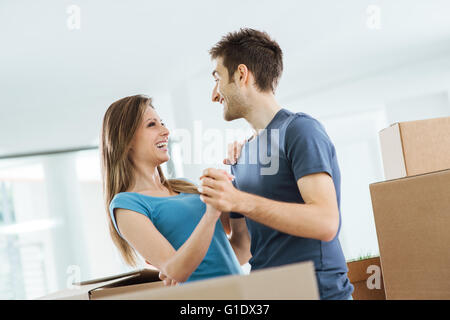 Happy smiling couple dansant dans leur belle maison neuve entourée par des boîtes en carton Banque D'Images