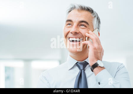 Confiant smiling businessman having a phone call sur son smart phone Banque D'Images