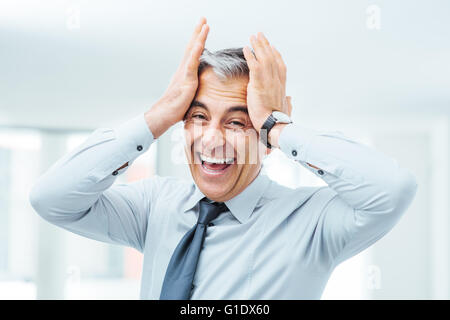 Cheerful businessman laughing imprudente et toucher son front Banque D'Images