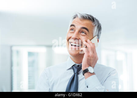 Confiant smiling businessman having a phone call sur son smart phone Banque D'Images