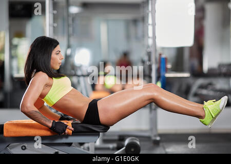 Jeune femme sportive au gymnase faire crunches abs sur un banc Banque D'Images