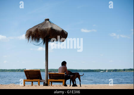 Petzow, Allemagne. 13 mai, 2016. ILLUSTRATION - Un homme est assis sur une chaise de plage avec son chien à côté de lui à l'Caputh lido et donne sur le lac Schwielowsee de Petzow, Allemagne, 13 mai 2016. La qualité de l'eau de tous les 251 lacs de baignade est excellente selon le ministère de l'consommateurs de Brandebourg. Photo : Klaus-Dietmar Gabbert/dpa/Alamy Live News Banque D'Images