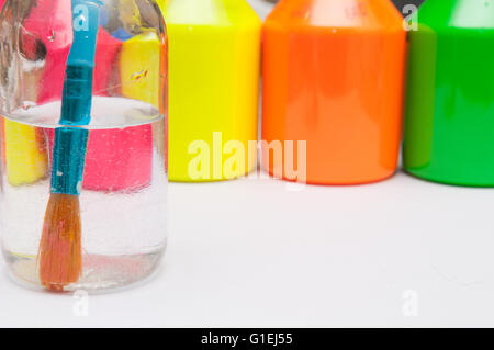 Le pinceau dans l'eau en face de l'enfant de couleur vive les pots de peinture pour l'activité d'une journée pluvieuse Banque D'Images