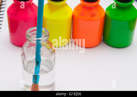 Le pinceau dans l'eau en face de l'enfant de couleur vive les pots de peinture pour l'activité d'une journée pluvieuse Banque D'Images