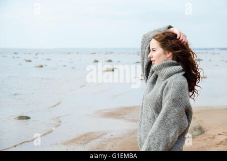 Jolie femme portant un cardigan chaud froid à la plage Banque D'Images