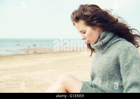 Jolie femme portant un cardigan chaud froid à la plage Banque D'Images