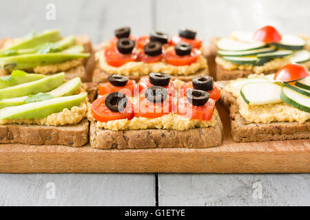 Houmous toasts avec la courgette et une tomate cerise, tomate cerise et d'olives noires et de l'avocat. Banque D'Images