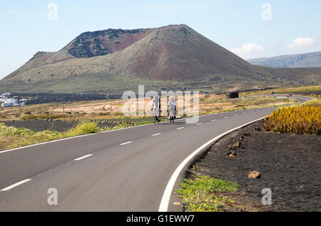 Les cyclistes sur route menant au cône du mont Corona volcano et Ye village, Haria, Lanzarote, îles Canaries, Espagne Banque D'Images