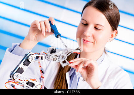 Parution du modèle. Ingénieur électrique femelle travaillant sur bras robotique. Banque D'Images