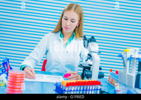 Parution du modèle. Assistant de laboratoire holding sample et prendre des notes dans le laboratoire. Banque D'Images