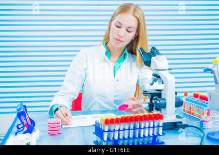 Parution du modèle. Assistant de laboratoire holding sample et prendre des notes dans le laboratoire. Banque D'Images