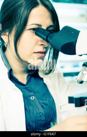 Parution du modèle. Femme technicienne de laboratoire à l'aide d'un microscope. Banque D'Images