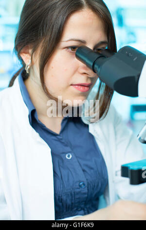 Parution du modèle. Femme technicienne de laboratoire à l'aide d'un microscope. Banque D'Images