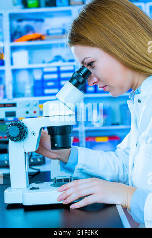 Parution du modèle. Femme technicienne de laboratoire à l'aide d'un microscope. Banque D'Images