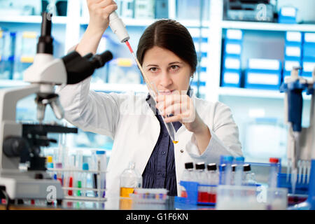 Parution du modèle. Femme technicienne de laboratoire à l'aide d'une pipette. Banque D'Images