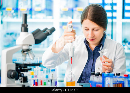 Parution du modèle. Femme technicienne de laboratoire à l'aide d'une pipette. Banque D'Images