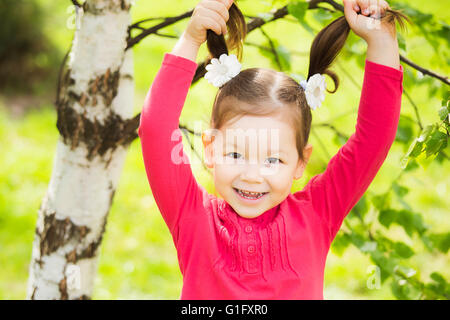 Closeup portrait of funny little girl. Rire enfant jouant avec ses cheveux. Carefree cheerful baby Banque D'Images