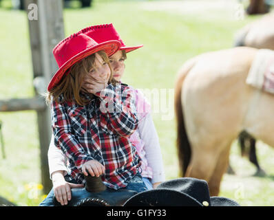 MITROV. REP tchèque - 7 mai 2016 : Deux cute little Girl with red hat à cheval sur le ranch. Banque D'Images