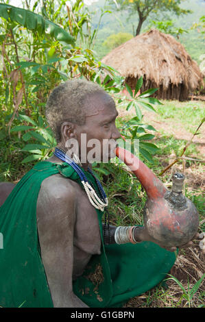 Personnes âgées Surma femme fumant à partir d'une calebasse, vallée de la rivière Omo, Kibish, Ethiopie Banque D'Images