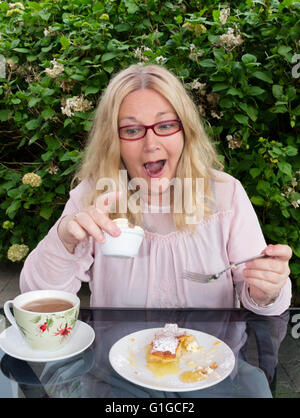 Woman eating cake avec tasse de café Banque D'Images