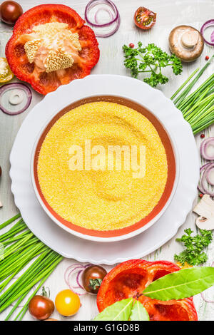 Plat de polenta et divers légumes et assaisonnement savoureux ingrédients pour la cuisine végétarienne sur la lumière de fond en bois rustique, Banque D'Images