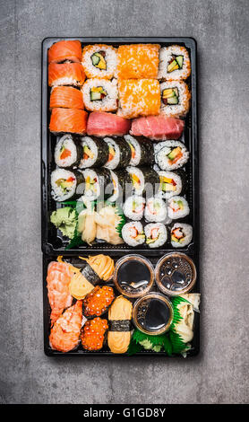 Divers sélection de sushis dans le bac d'emballage noir sur fond noir en gris, vue du dessus. Vue de dessus de la rédaction. Cuisine Asiatique et japonaise Banque D'Images