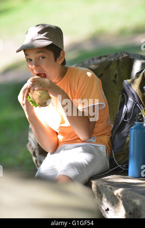 Jeune garçon en train de manger un sandwich après une promenade, France Banque D'Images