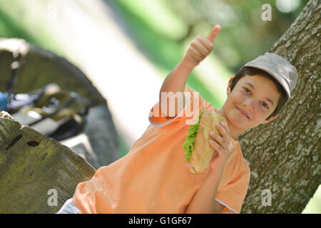 Jeune garçon en train de manger un sandwich après une promenade, France Banque D'Images