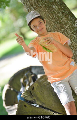 Jeune garçon en train de manger un sandwich après une promenade, France Banque D'Images