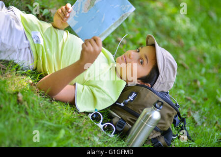 Jeune garçon allongé dans l'herbe en regardant une carte Banque D'Images