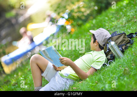 Jeune garçon allongé dans l'herbe en regardant une carte Banque D'Images