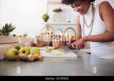 Jolie jeune femme clive fruits frais pour smoothie. Femme travaillant au bar à jus. Banque D'Images