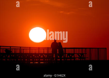 Pays de Galles Royaume-uni Aberystwyth , Ceredigion, dimanche 15 mai 2016 UK weather : un spectaculaire coucher de soleil sur les chiffres de population qui se profile sur la jetée à Aberystwyth, sur la côte de la Baie de Cardigan, l'ouest du pays de Galles. La météo a été plus frais mais lumineux jours précédents, et la prévision est pour une période d'instabilité, venteux et pluvieux à se propager dans de l'ouest par le milieu de la semaine Crédit photo : Keith Morris / Alamy Live News Banque D'Images