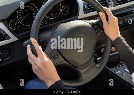 Femme mains tenant le volant de voiture de luxe Banque D'Images