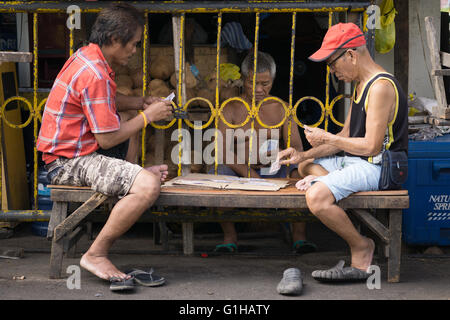 Des hommes jouant aux cartes dans le marché du carbone situé au centre-ville de Cebu City, Philippines Banque D'Images