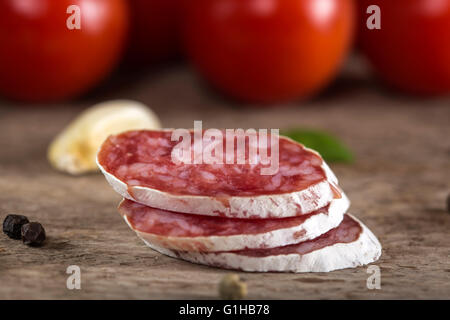 Close up de tranches de salami italien avec des épices et des légumes sur fond de bois rustique Banque D'Images