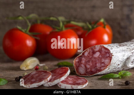 Salami italien avec des épices et des légumes sur fond de bois rustique Banque D'Images