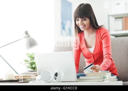 Young smiling woman at home à l'aide d'un ordinateur portable et des achats en ligne avec une carte de crédit, de commerce et de communication concept Banque D'Images