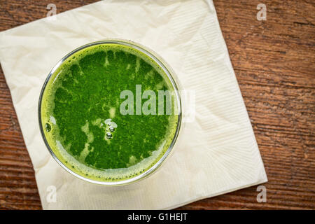 Jus de légumes verts frais de concombre, les épinards et le chou - Vue de dessus d'un verre avec serviette contre bois rustique Banque D'Images