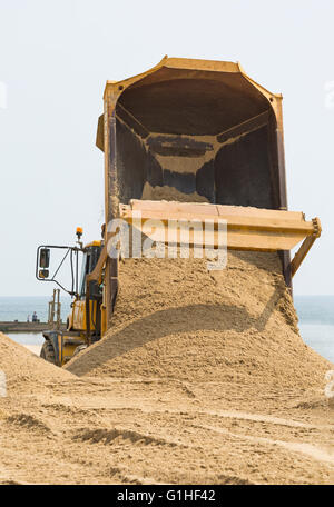 Le pourboire du sable du sable en mouvement du camion-benne articulé sur la plage de Bournemouth glissement suivants en Avril Banque D'Images
