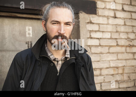 Homme barbu cigarette plus vieux mur de briques, outdoor portrait with selective focus Banque D'Images