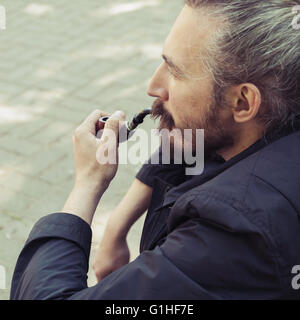 Pipe homme barbu, square outdoor portrait with selective focus et vintage photo, filtre de correction tonale old style effe Banque D'Images